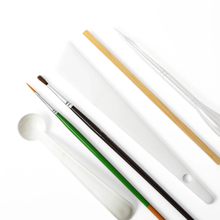 Specialized craft tools for traditional Japanese kintsugi pottery repair, featuring fine art brushes and plastic spatulas