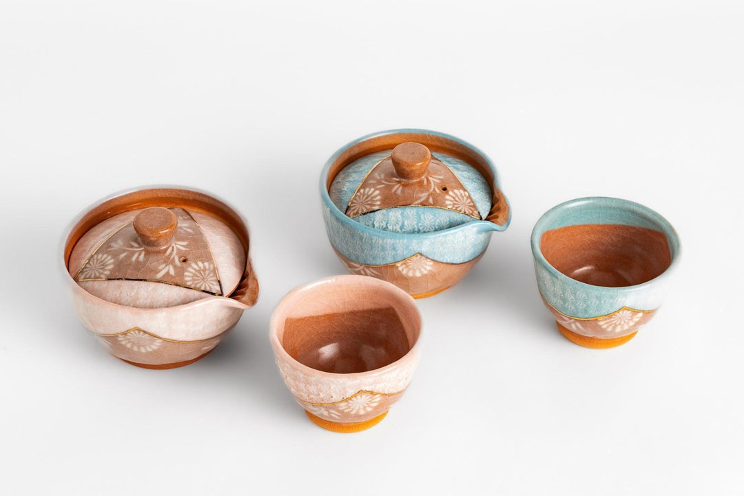 Handcrafted Japanese pottery set with lidded bowls and cups in soft pink and blue glaze with carved floral design