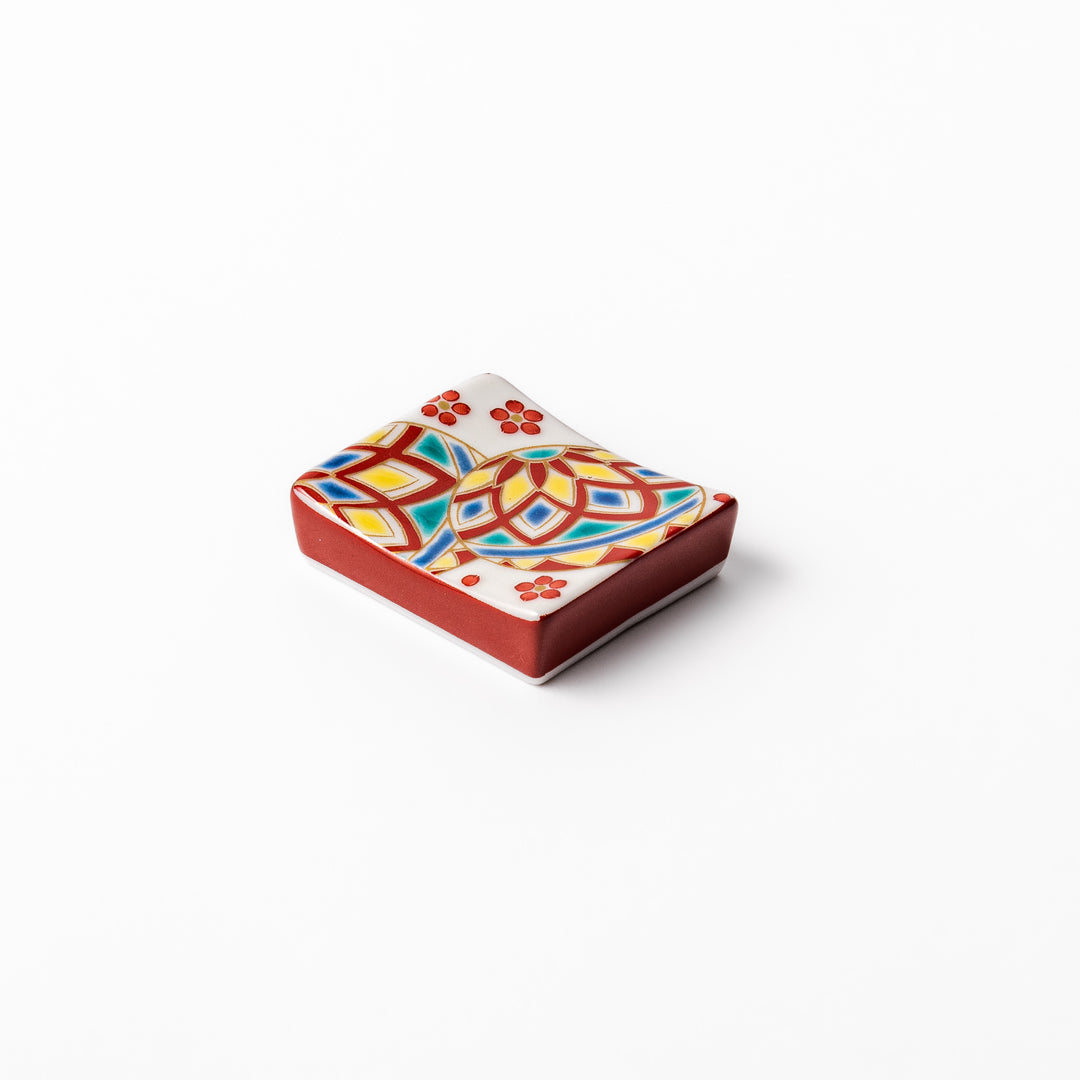 Rectangular Japanese ceramic chopstick rest adorned with colorful temari ball patterns and red floral accents, bringing vibrant charm to any dining table.