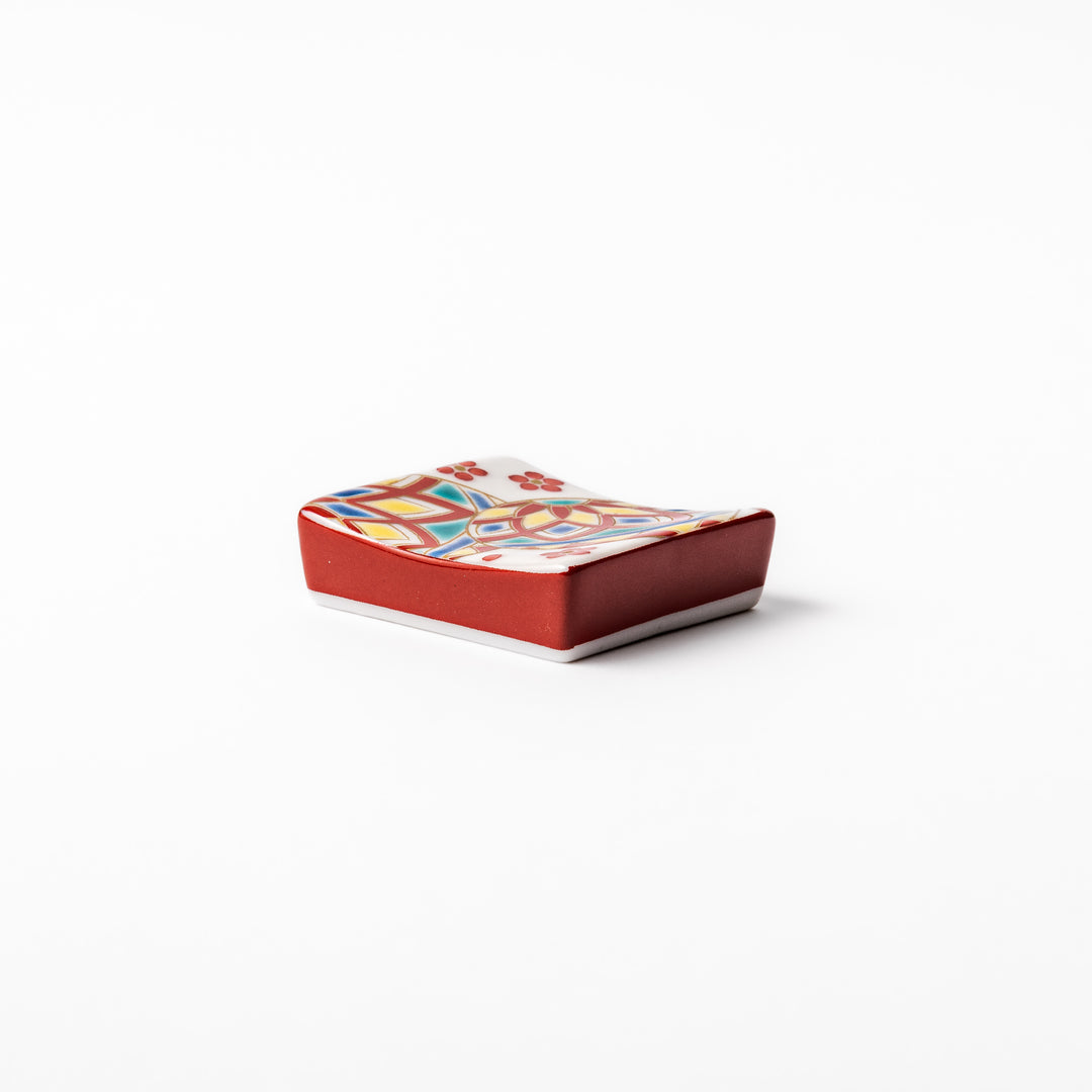 Rectangular Japanese ceramic chopstick rest adorned with colorful temari ball patterns and red floral accents, bringing vibrant charm to any dining table.