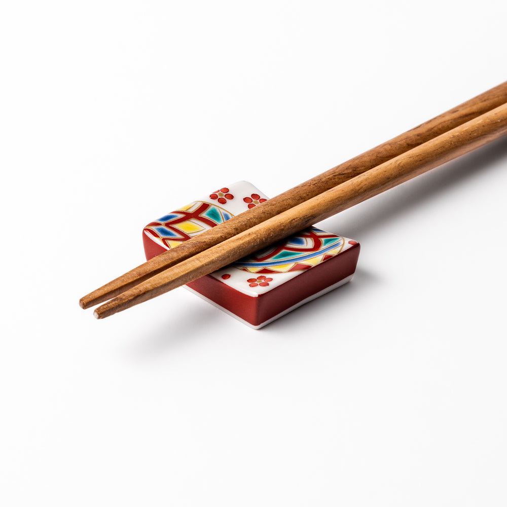 Rectangular Japanese ceramic chopstick rest adorned with colorful temari ball patterns and red floral accents, bringing vibrant charm to any dining table.