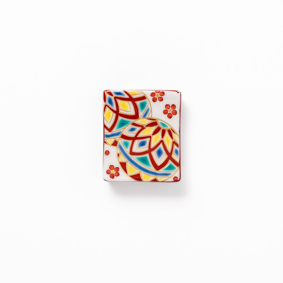 Rectangular Japanese ceramic chopstick rest adorned with colorful temari ball patterns and red floral accents, bringing vibrant charm to any dining table.