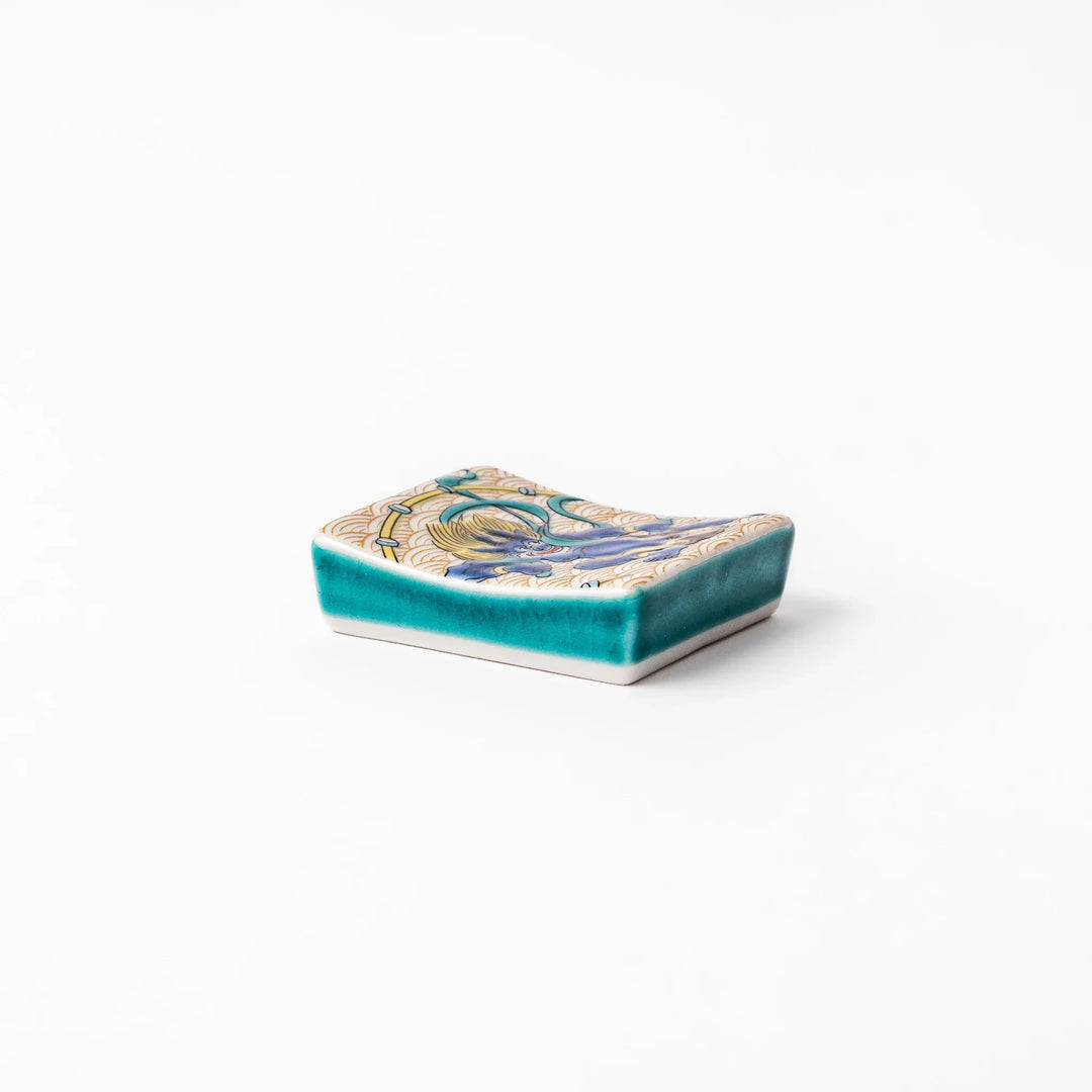 Japanese porcelain chopstick rest featuring the Thunder God design with blue figure and gold wave pattern background.