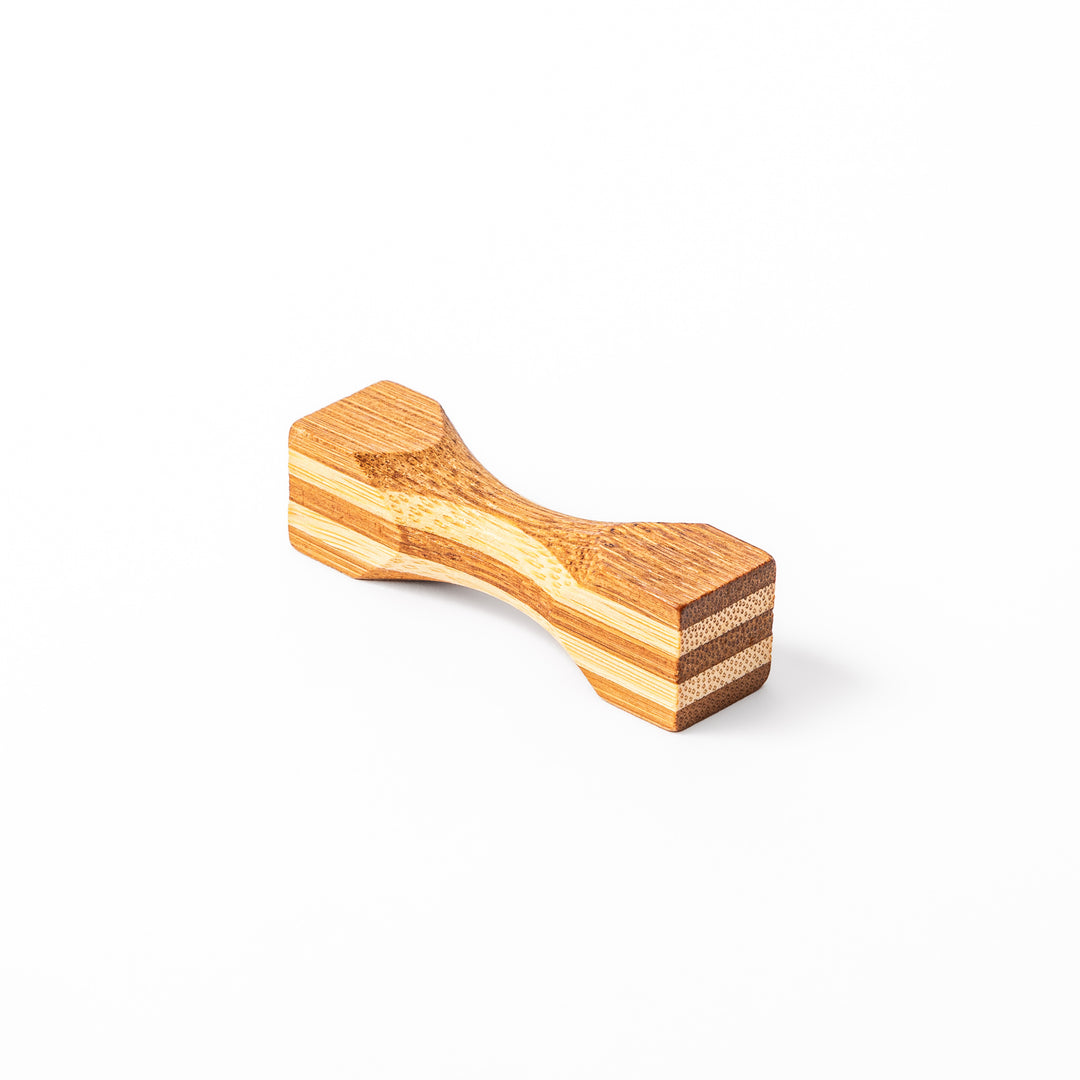 Japanese Tsuzumi bamboo chopstick rest with a hand carved hourglass shape and layered wood grain for dining tables