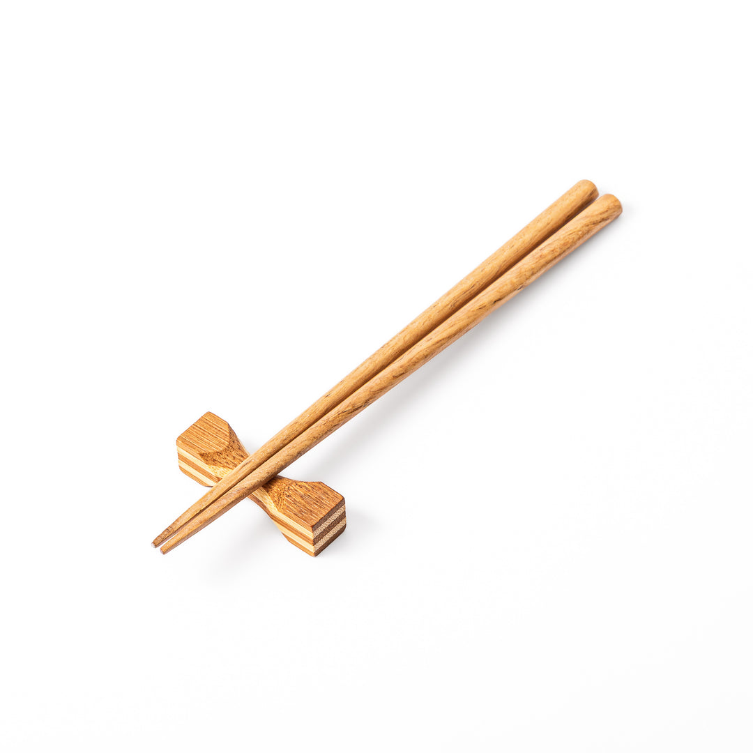Japanese Tsuzumi bamboo chopstick rest with a hand carved hourglass shape and layered wood grain for dining tables