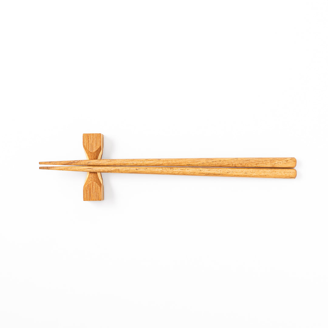 Japanese Tsuzumi bamboo chopstick rest with a hand carved hourglass shape and layered wood grain for dining tables