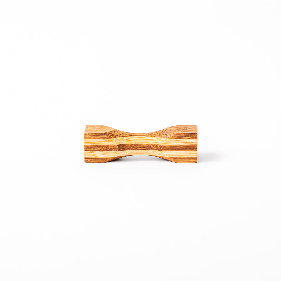 Japanese Tsuzumi bamboo chopstick rest with a hand carved hourglass shape and layered wood grain for dining tables