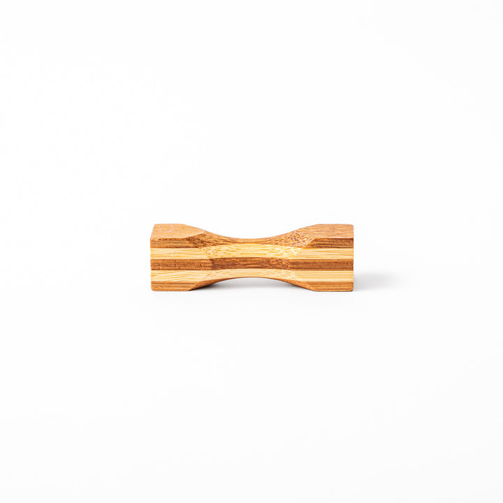Japanese Tsuzumi bamboo chopstick rest with a hand carved hourglass shape and layered wood grain for dining tables