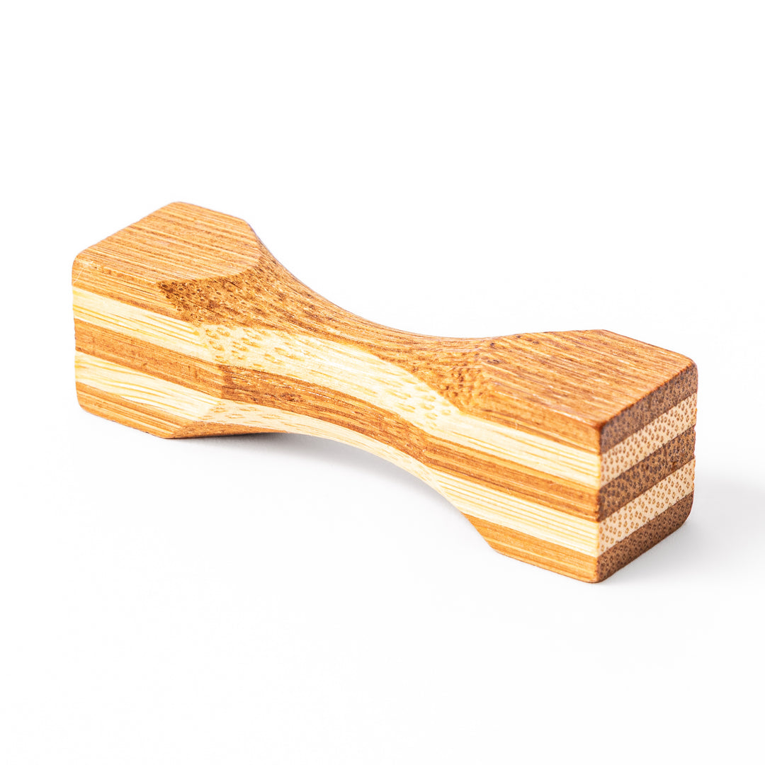 Japanese Tsuzumi bamboo chopstick rest with a hand carved hourglass shape and layered wood grain for dining tables