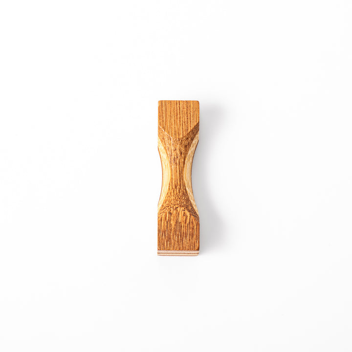 Japanese Tsuzumi bamboo chopstick rest with a hand carved hourglass shape and layered wood grain for dining tables