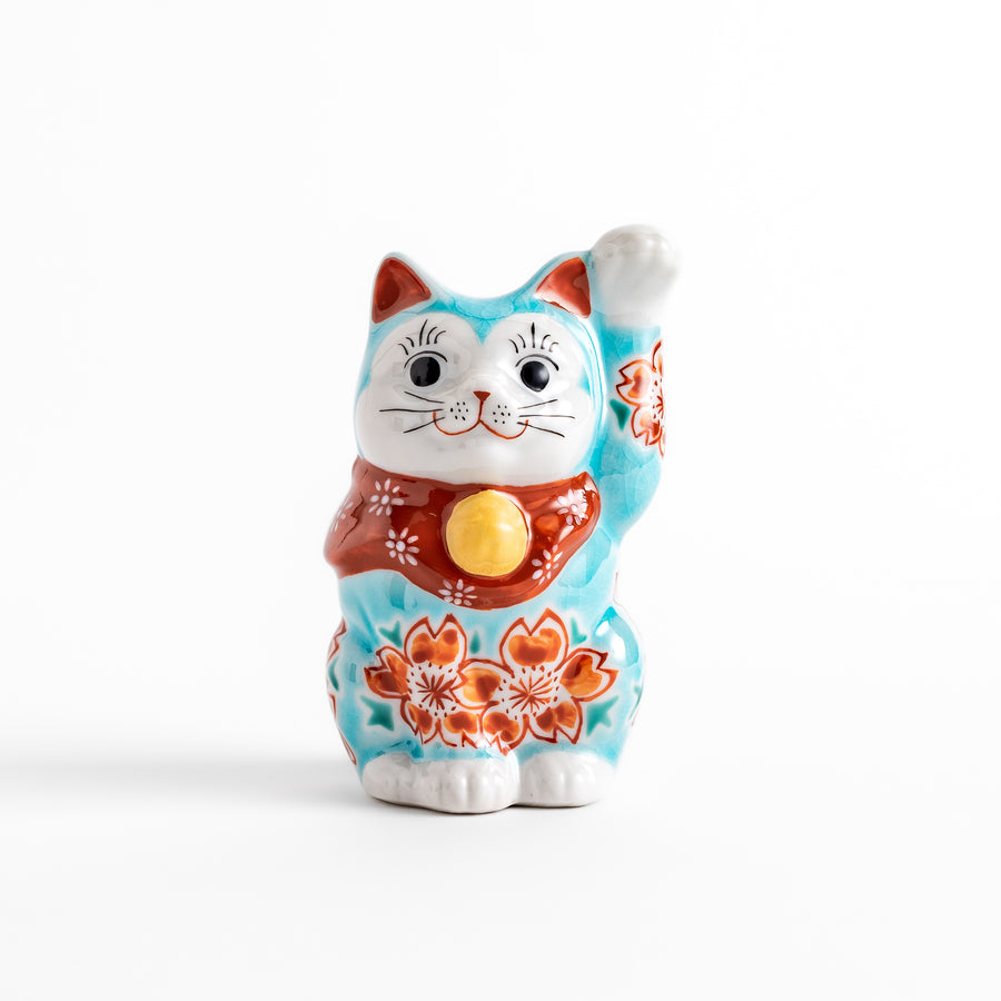 Vibrant Turkish blue Maneki Neko figurine adorned with floral patterns in orange and white, featuring a golden bell and a raised paw, symbolizing good fortune and prosperity.