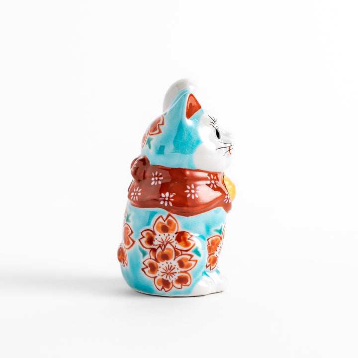 Vibrant Turkish blue Maneki Neko figurine adorned with floral patterns in orange and white, featuring a golden bell and a raised paw, symbolizing good fortune and prosperity.