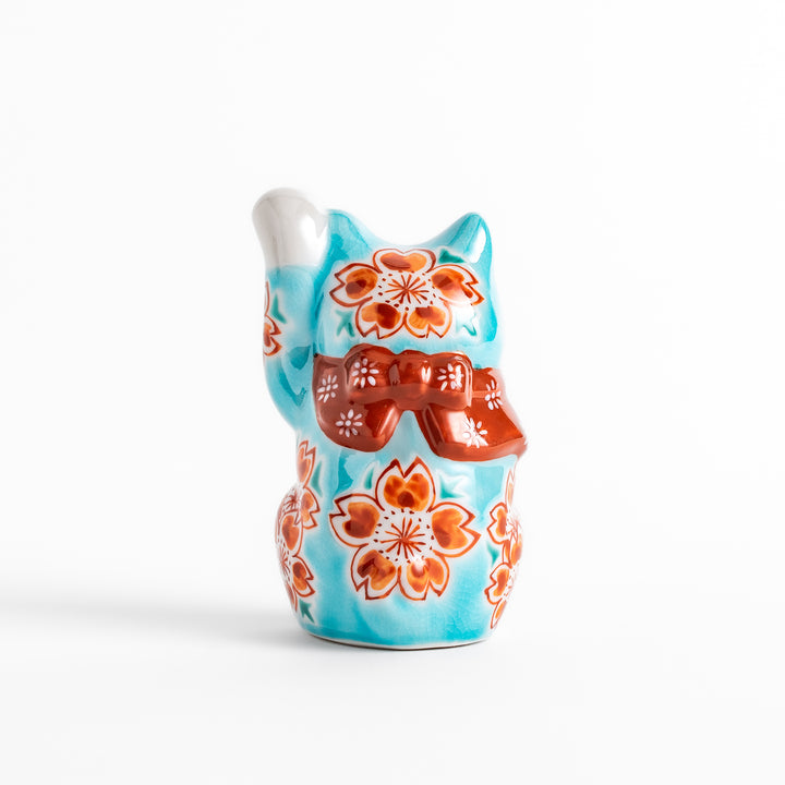 Vibrant Turkish blue Maneki Neko figurine adorned with floral patterns in orange and white, featuring a golden bell and a raised paw, symbolizing good fortune and prosperity.