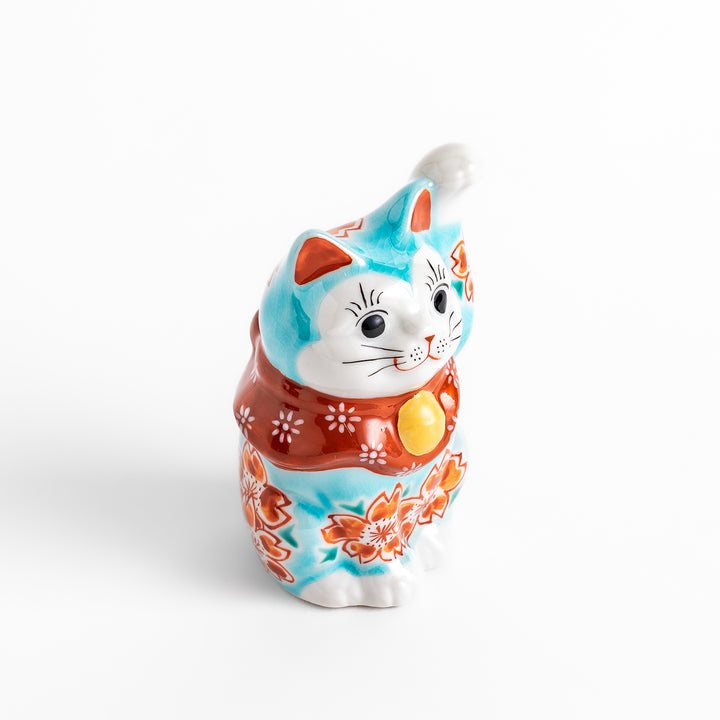 Vibrant Turkish blue Maneki Neko figurine adorned with floral patterns in orange and white, featuring a golden bell and a raised paw, symbolizing good fortune and prosperity.