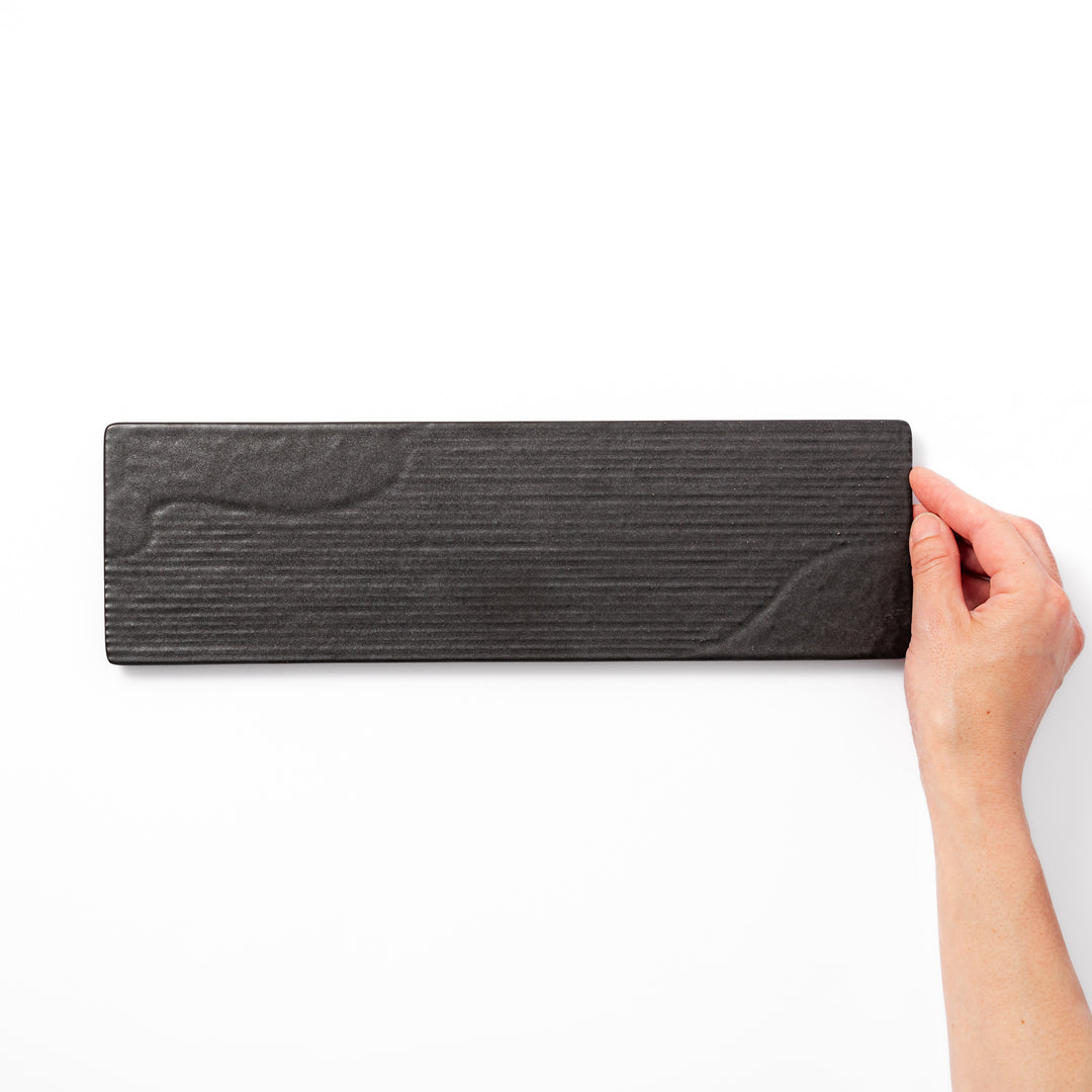 Rectangular black ceramic serving plate with a subtle ridged woodgrain texture, perfect for stylish Japanese meals and contemporary plating.