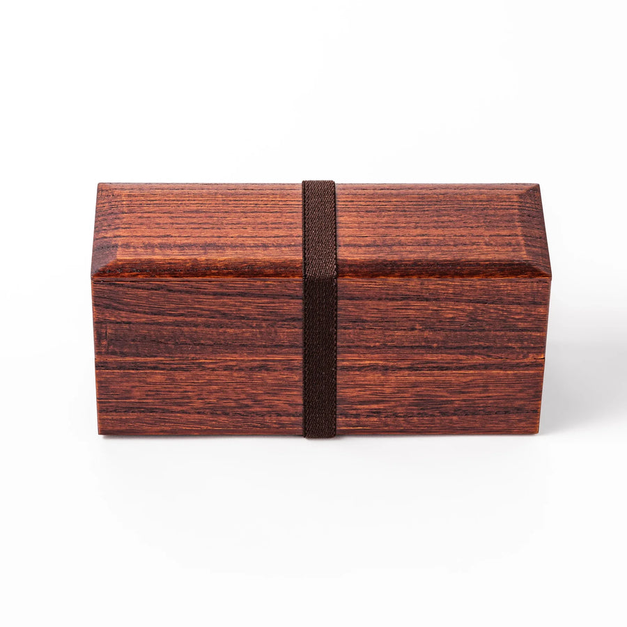 Dark brown two-tier bento box made from richly grained paulownia wood, secured with a black elastic band, ideal for stylish Japanese lunches.