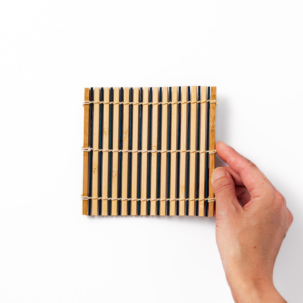 Two-tone bamboo coaster with alternating dark and natural bamboo slats, hand-tied with twine—perfect for protecting surfaces with Japanese flair.
