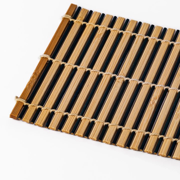 Two-tone bamboo coaster with alternating dark and natural bamboo slats, hand-tied with twine—perfect for protecting surfaces with Japanese flair.