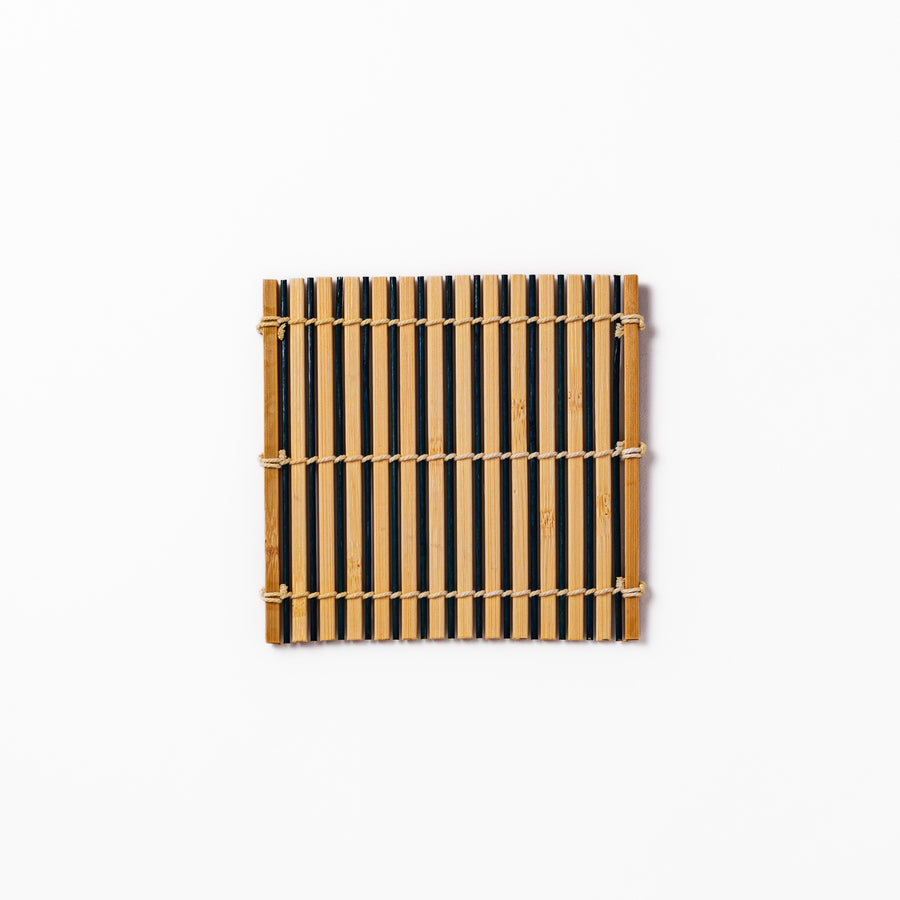 Two-tone bamboo coaster with alternating dark and natural bamboo slats, hand-tied with twine—perfect for protecting surfaces with Japanese flair.
