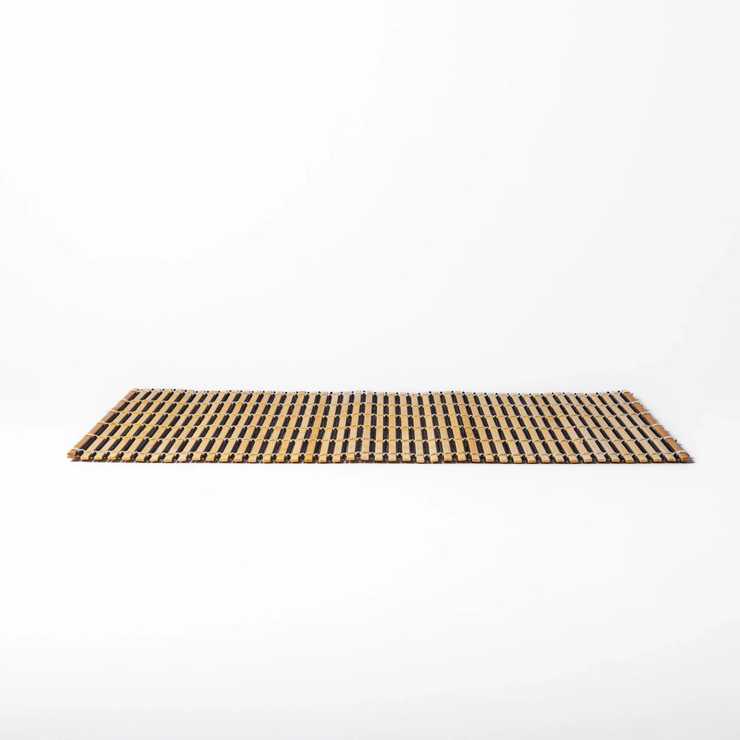 Two-tone bamboo table mat with alternating light and dark slats, tightly woven with white cord—ideal for adding texture to your Japanese table setting.