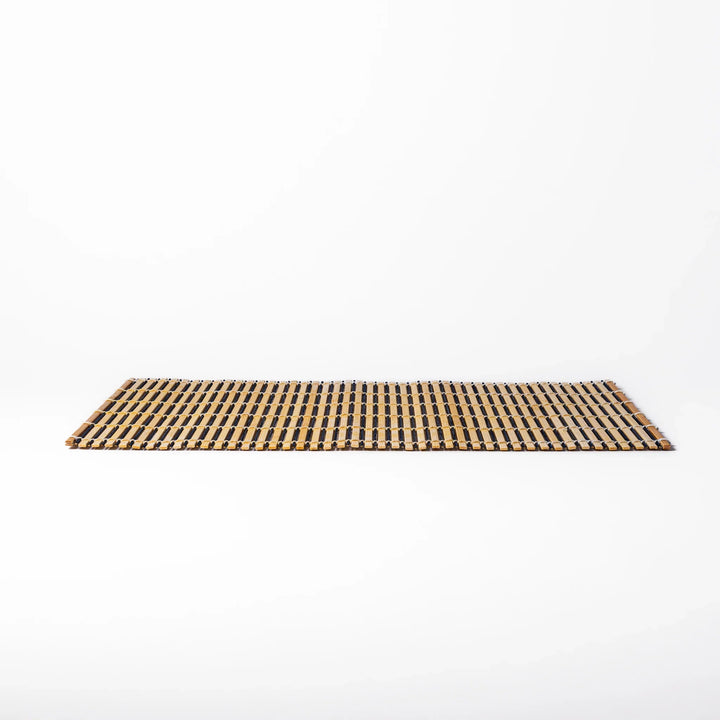 Two-tone bamboo table mat with alternating light and dark slats, tightly woven with white cord—ideal for adding texture to your Japanese table setting.