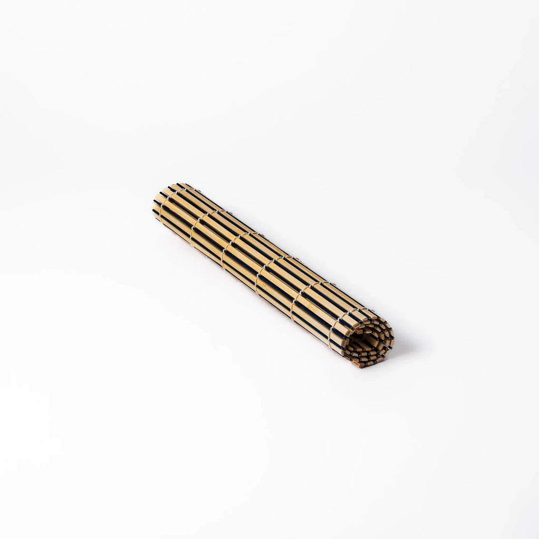 Two-tone bamboo table mat with alternating light and dark slats, tightly woven with white cord—ideal for adding texture to your Japanese table setting.