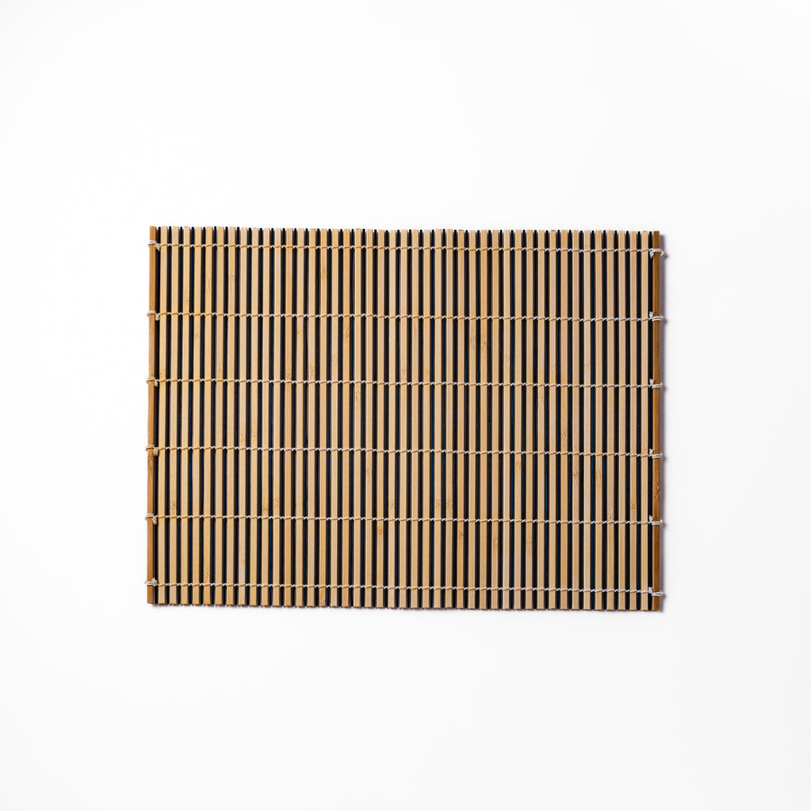 Two-tone bamboo table mat with alternating light and dark slats, tightly woven with white cord—ideal for adding texture to your Japanese table setting.