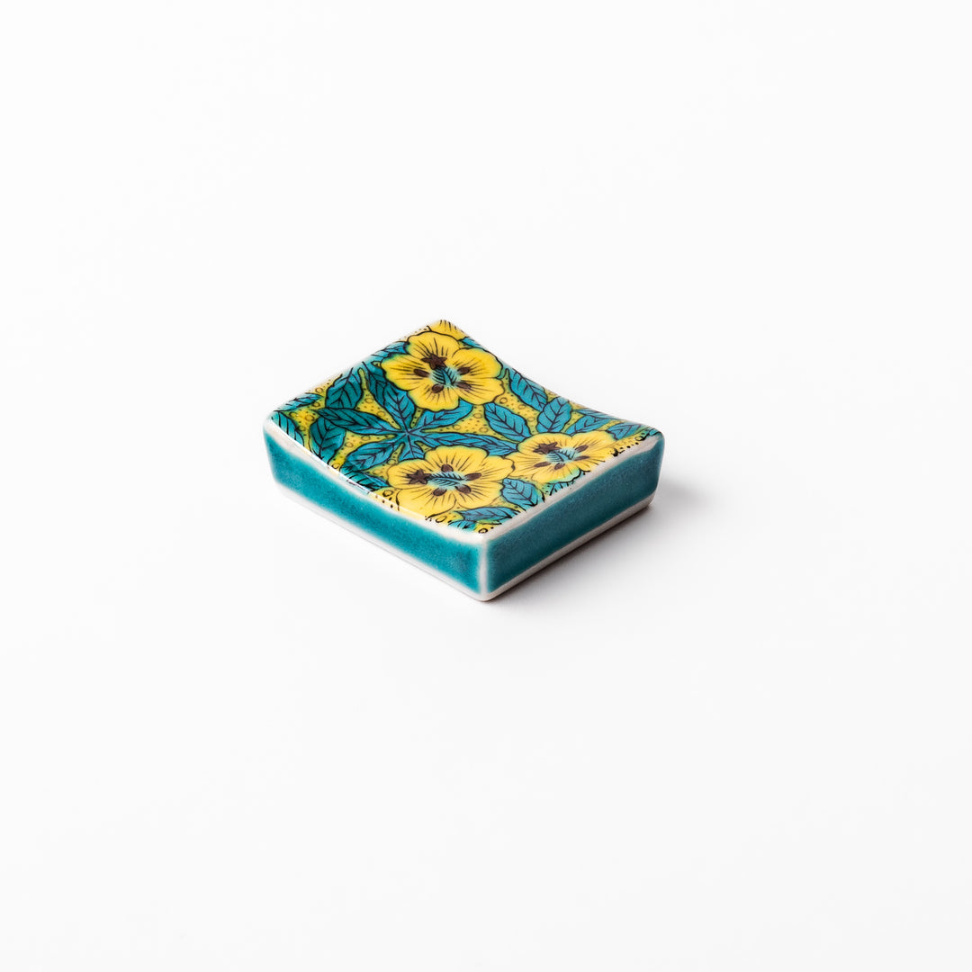 Rectangular Japanese ceramic chopstick rest decorated with vivid yellow floral design and teal leaves, bringing elegance and color to your dining table.