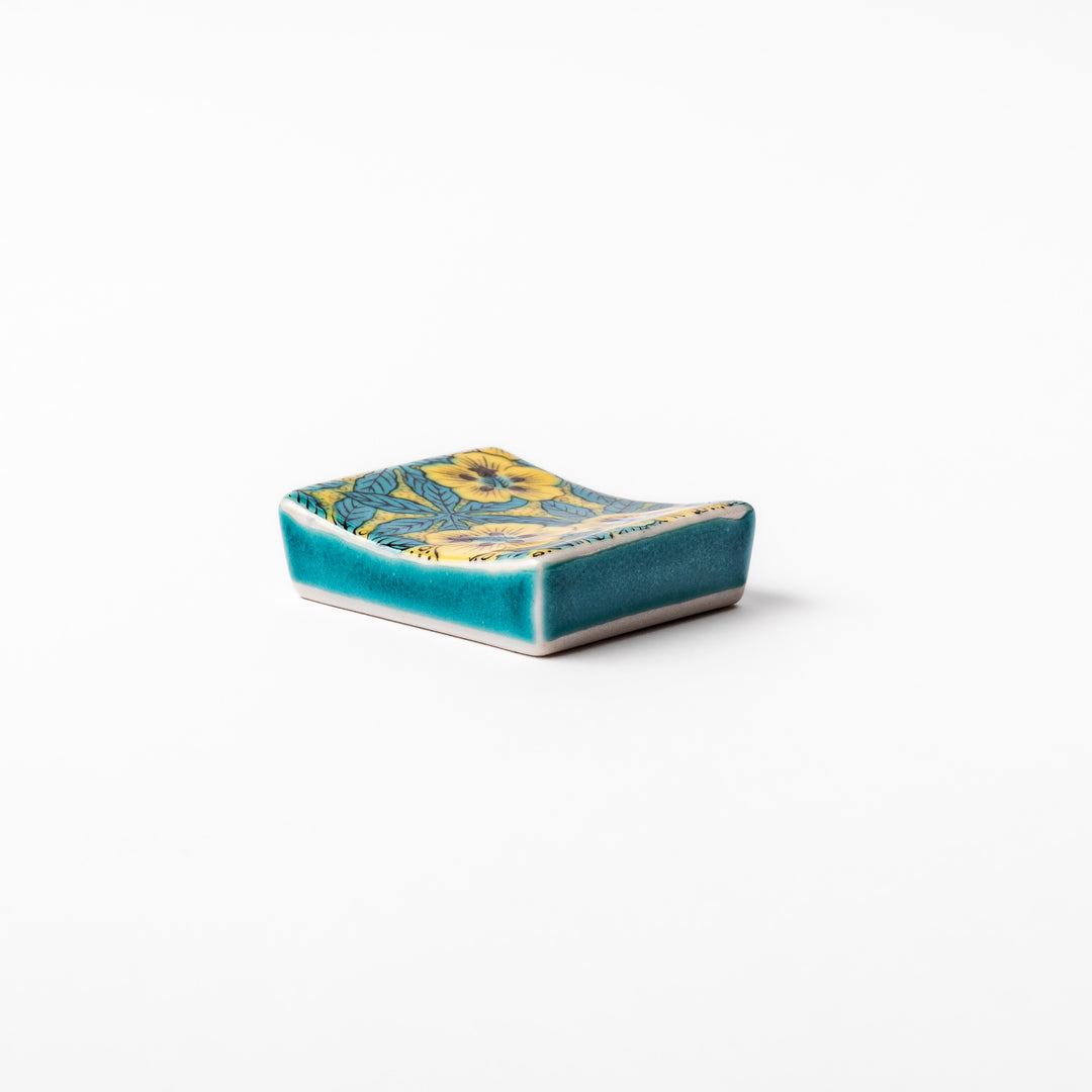 Rectangular Japanese ceramic chopstick rest decorated with vivid yellow floral design and teal leaves, bringing elegance and color to your dining table.
