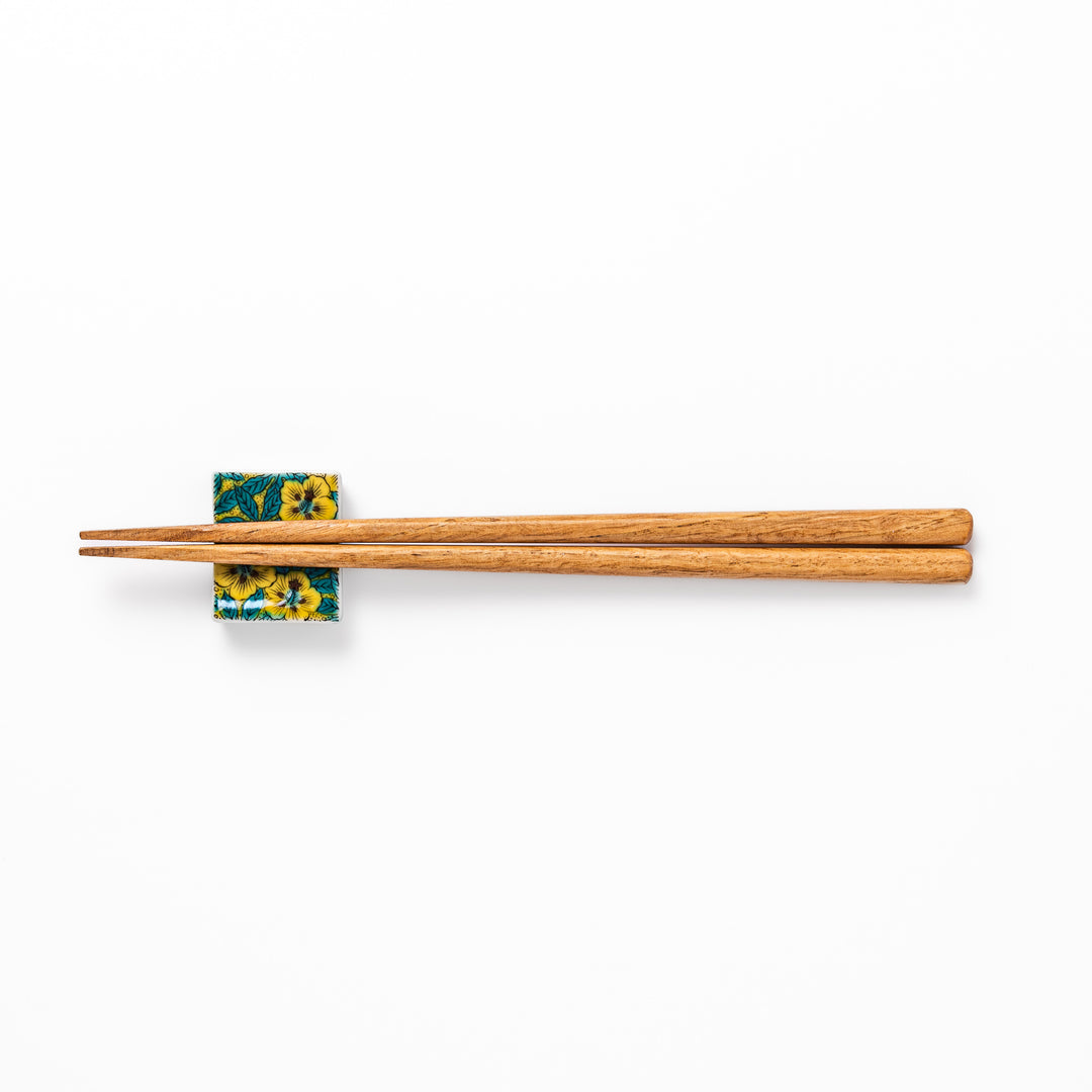 Rectangular Japanese ceramic chopstick rest decorated with vivid yellow floral design and teal leaves, bringing elegance and color to your dining table.