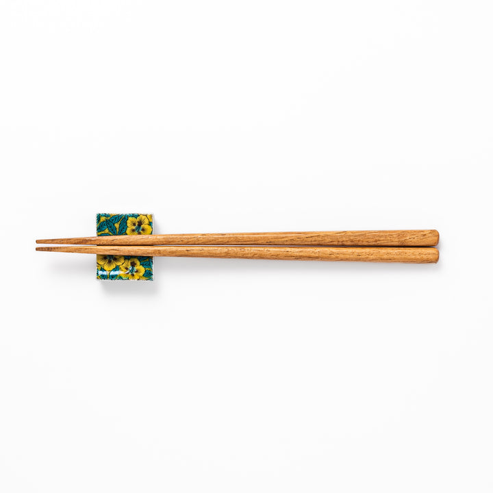 Rectangular Japanese ceramic chopstick rest decorated with vivid yellow floral design and teal leaves, bringing elegance and color to your dining table.