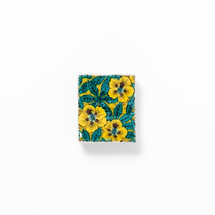 Rectangular Japanese ceramic chopstick rest decorated with vivid yellow floral design and teal leaves, bringing elegance and color to your dining table.