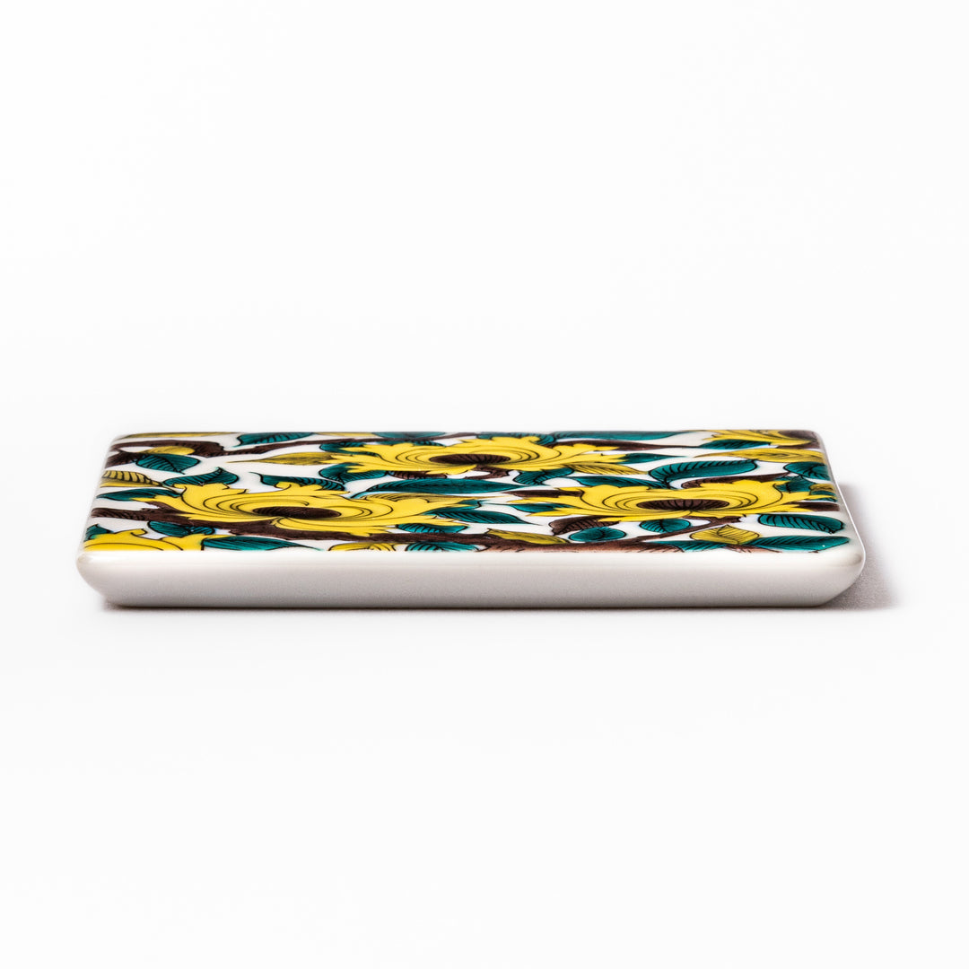 Square Japanese ceramic coaster adorned with vivid yellow peony blooms and teal leaves, adding elegance and charm to any dining table setting.