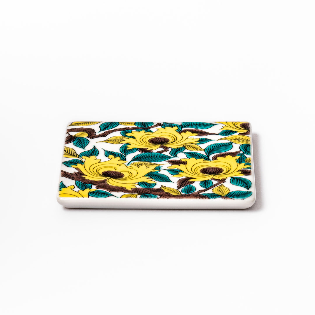 Square Japanese ceramic coaster adorned with vivid yellow peony blooms and teal leaves, adding elegance and charm to any dining table setting.