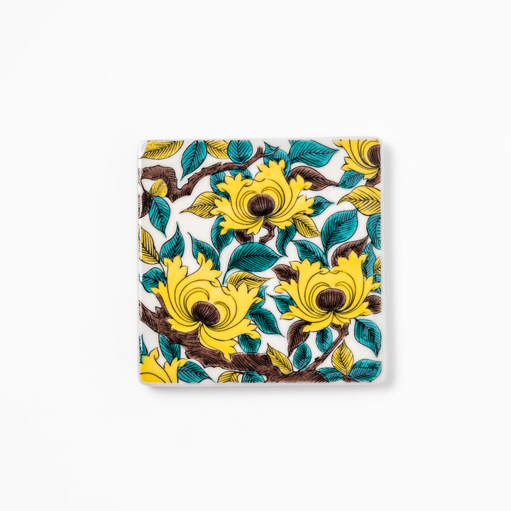 Square Japanese ceramic coaster adorned with vivid yellow peony blooms and teal leaves, adding elegance and charm to any dining table setting.