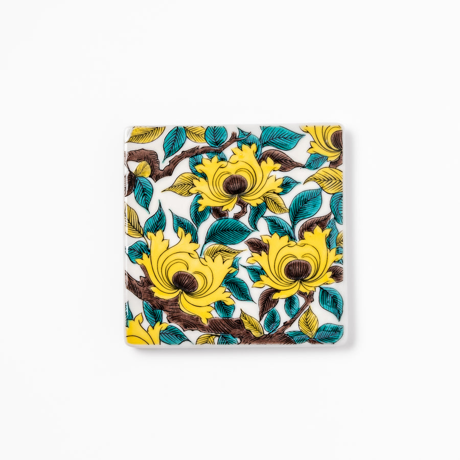 Square Japanese ceramic coaster adorned with vivid yellow peony blooms and teal leaves, adding elegance and charm to any dining table setting.
