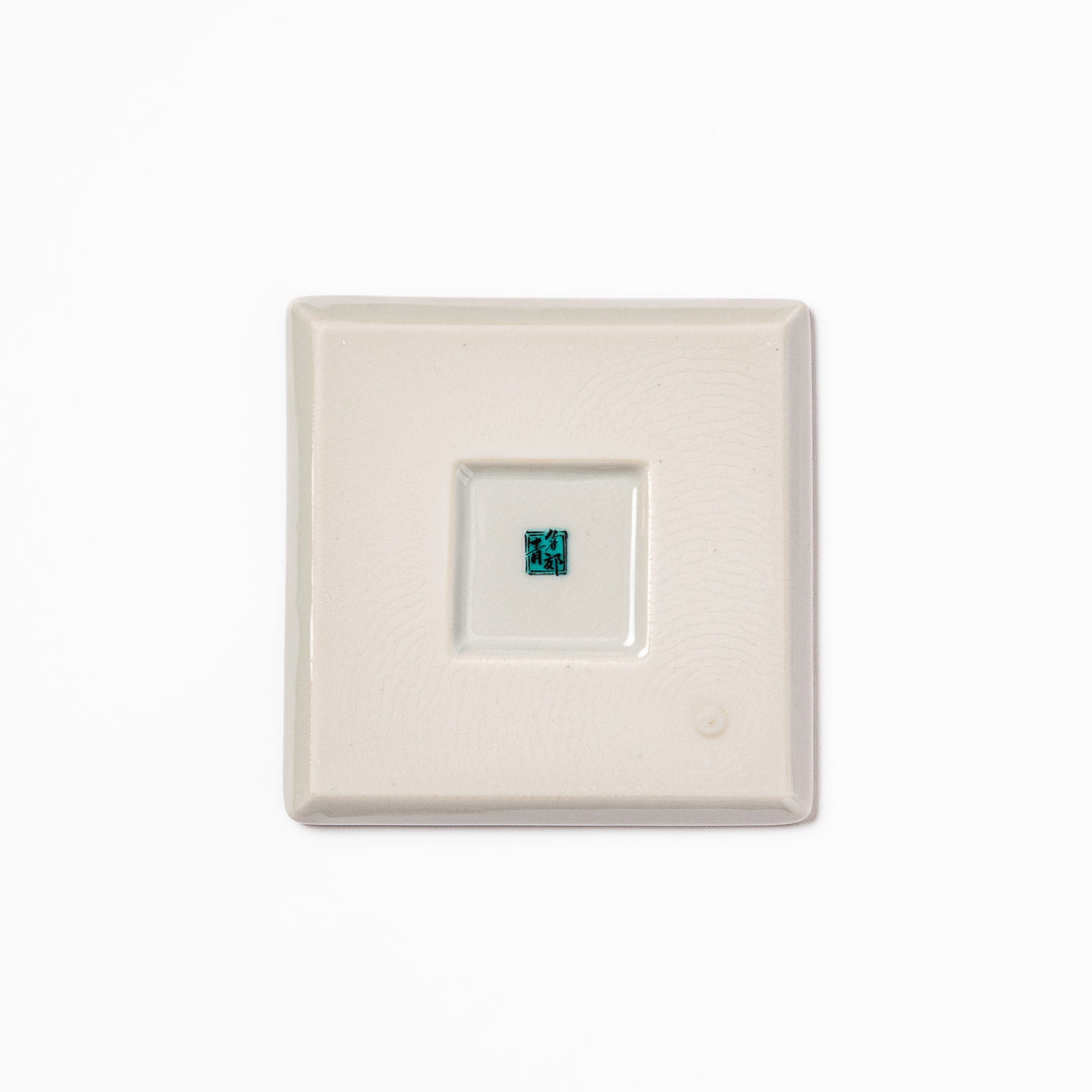 Square Japanese ceramic coaster adorned with vivid yellow peony blooms and teal leaves, adding elegance and charm to any dining table setting.