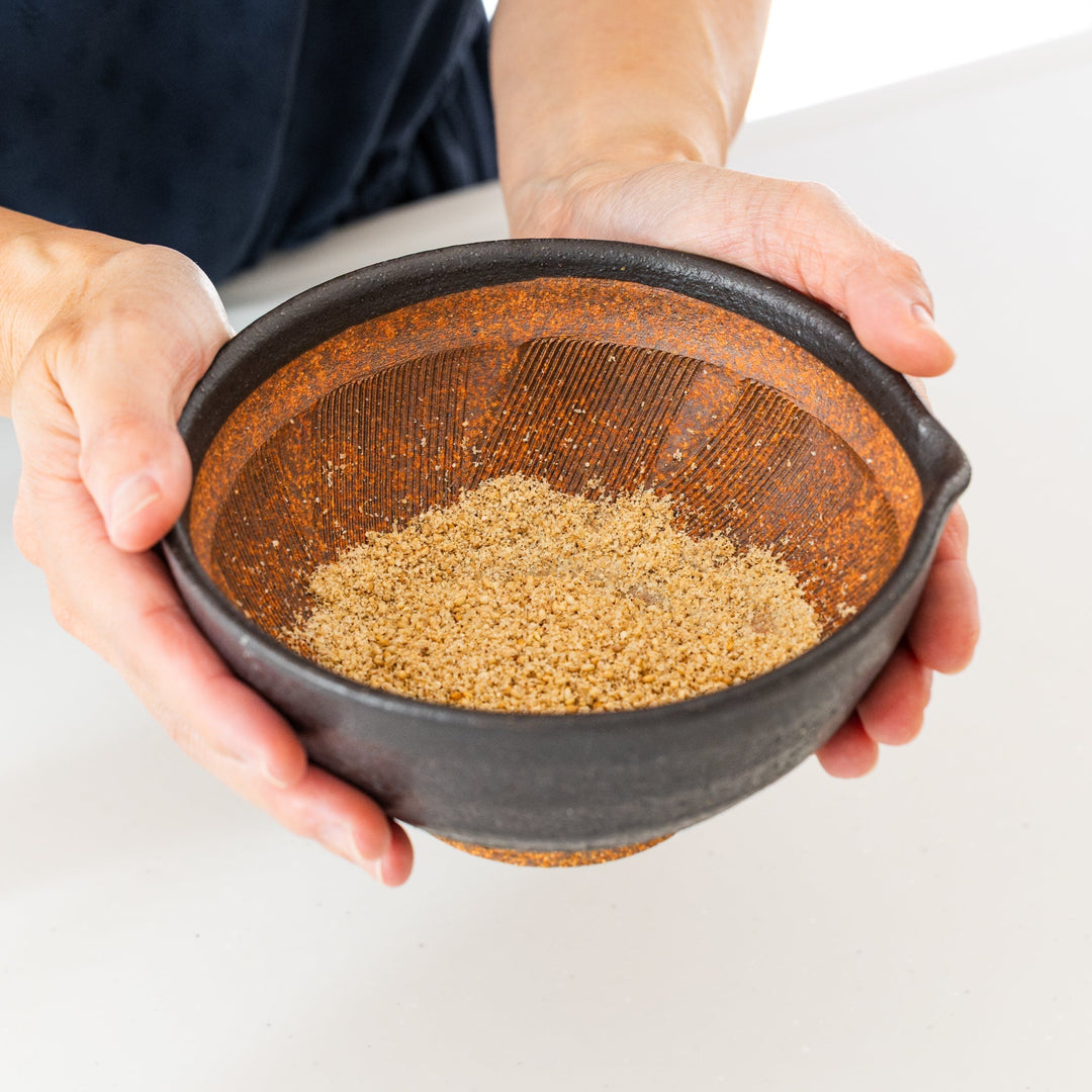 Japanese suribachi mortar holding freshly ground sesame seeds with textured ridges for smooth grinding
