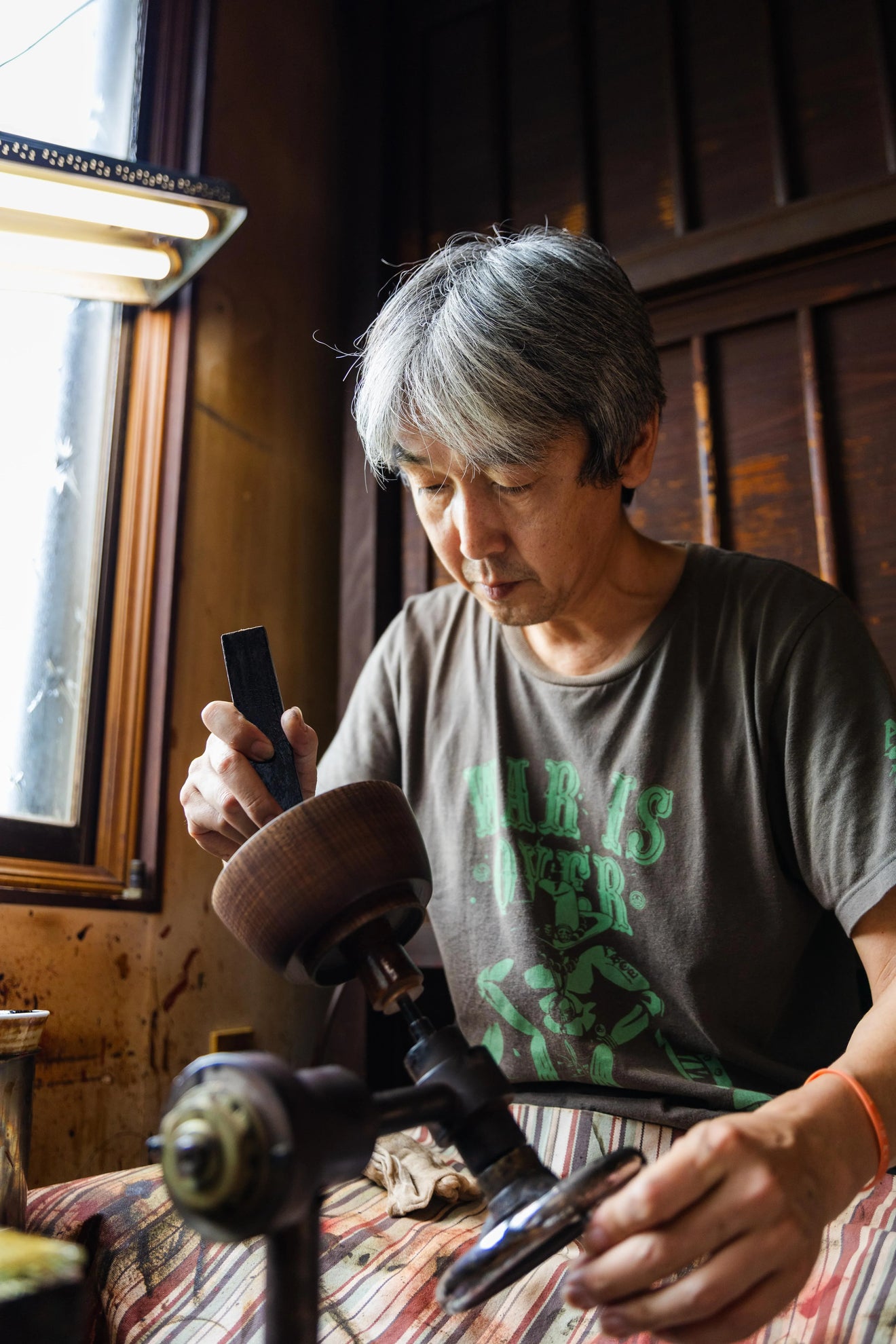 Japanese artisan applying urushi lacquer to a wooden miso soup bowl in a traditional workshop