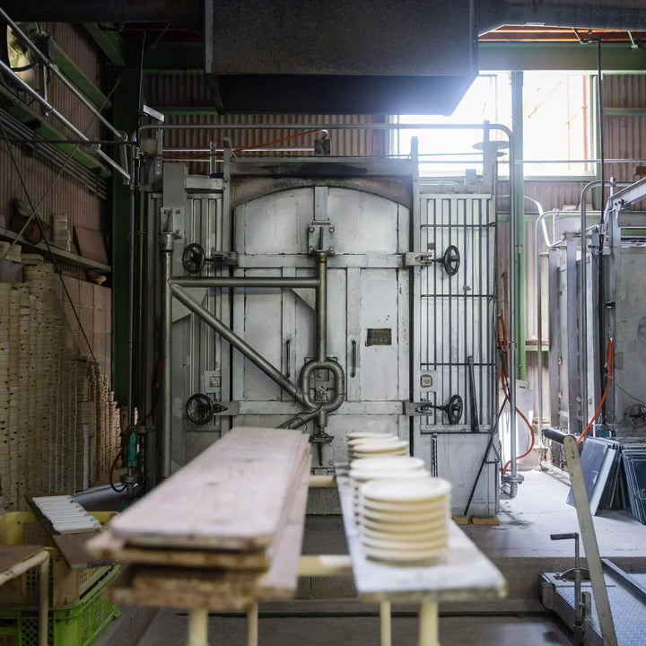 Ceramic plates arranged on boards in front of the kiln during the artisan process of preparing pieces for firing