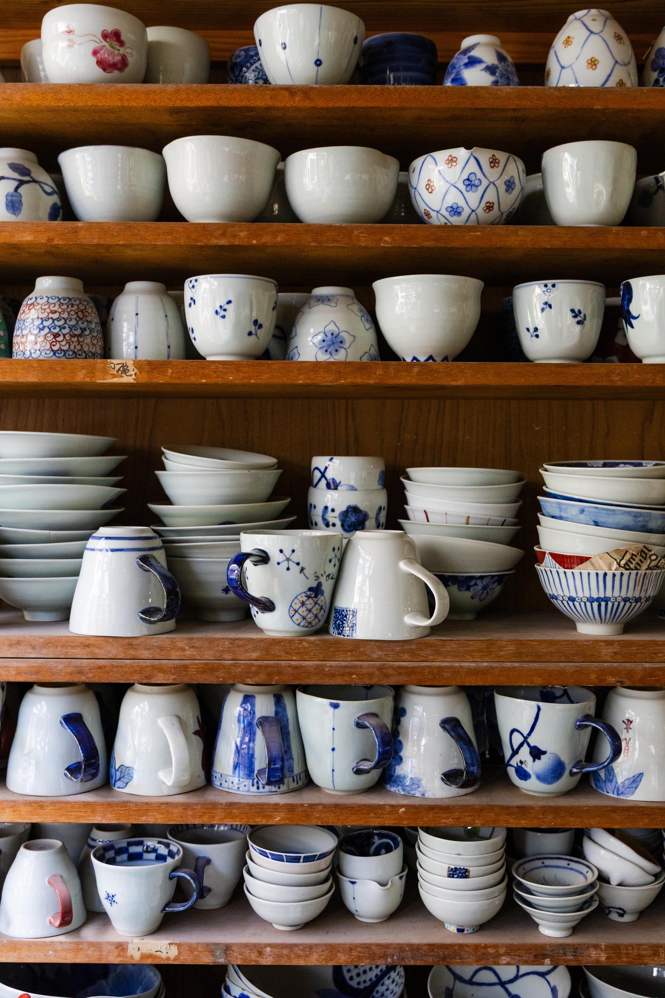 Shelves filled with handcrafted Japanese ceramic bowls cups and mugs with traditional blue and white patterns