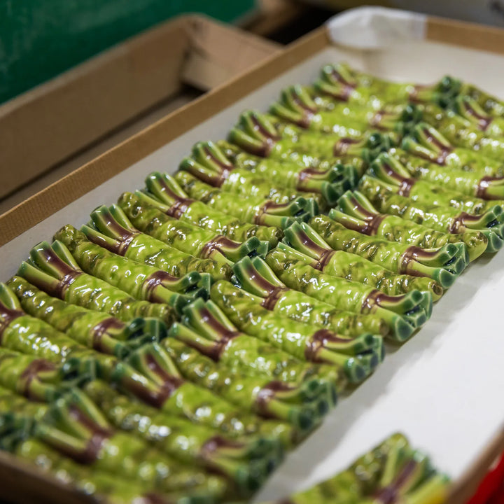 Rows of glossy ceramic chopstick rests shaped like bamboo arranged after glazing in the workshop