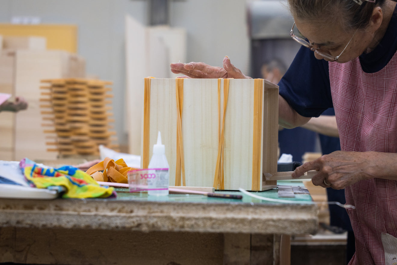 Japanese craftsperson assembling a paulownia wooden box held together with rubber bands at Masuda Kiribako workshop in Fukuoka Japan