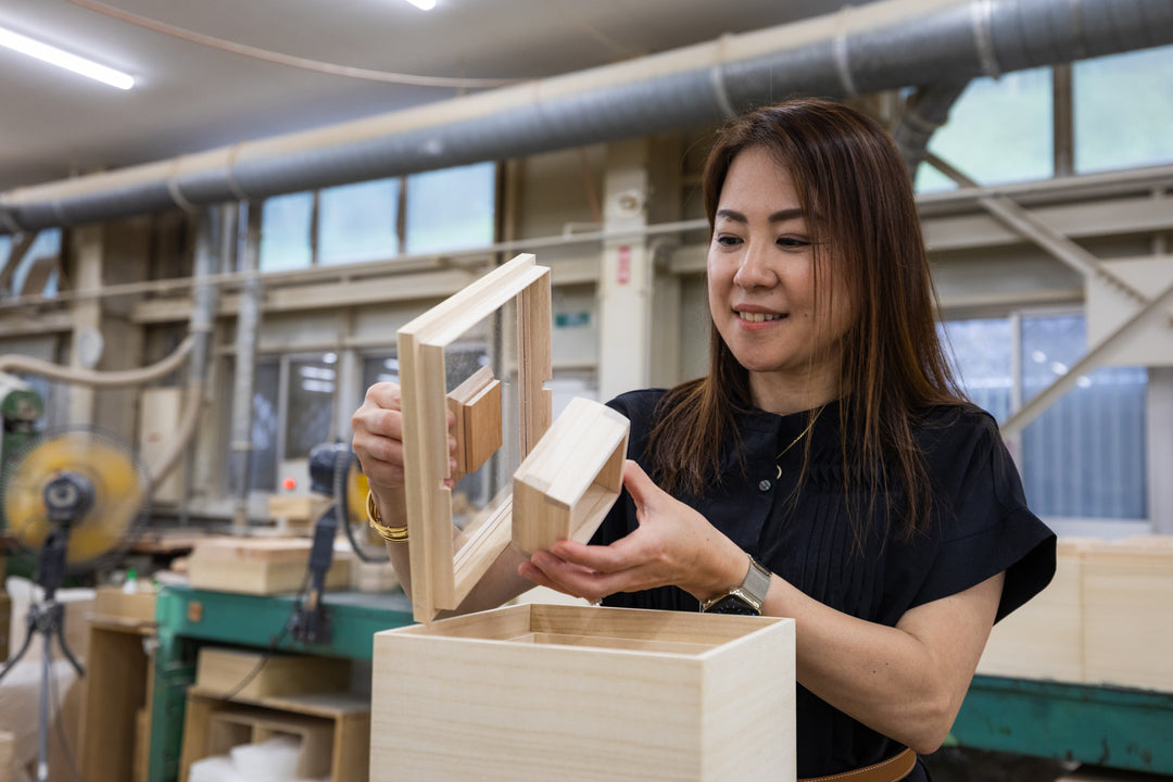 Nami from JOC examining a handcrafted paulownia wooden rice box with a clear acrylic lid inside the Masuda Kiribako workshop in Fukuoka Japan