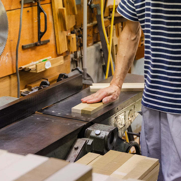 Wood artisan smoothing hinoki wood on a jointer in a traditional workshop