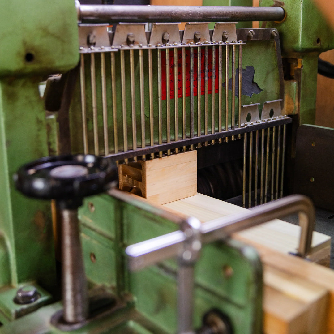 Wood block being shaped inside a traditional woodworking machine in a Japanese workshop