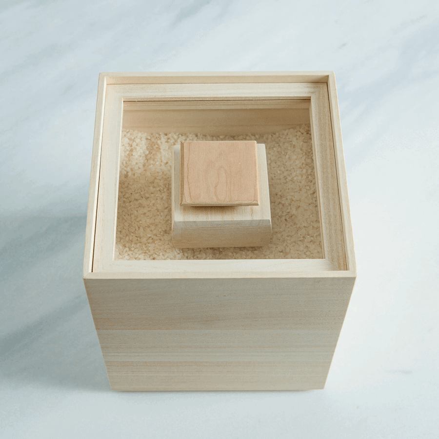 Paulownia wood rice container with inner lid, filled with rice for traditional Japanese kitchen storage.