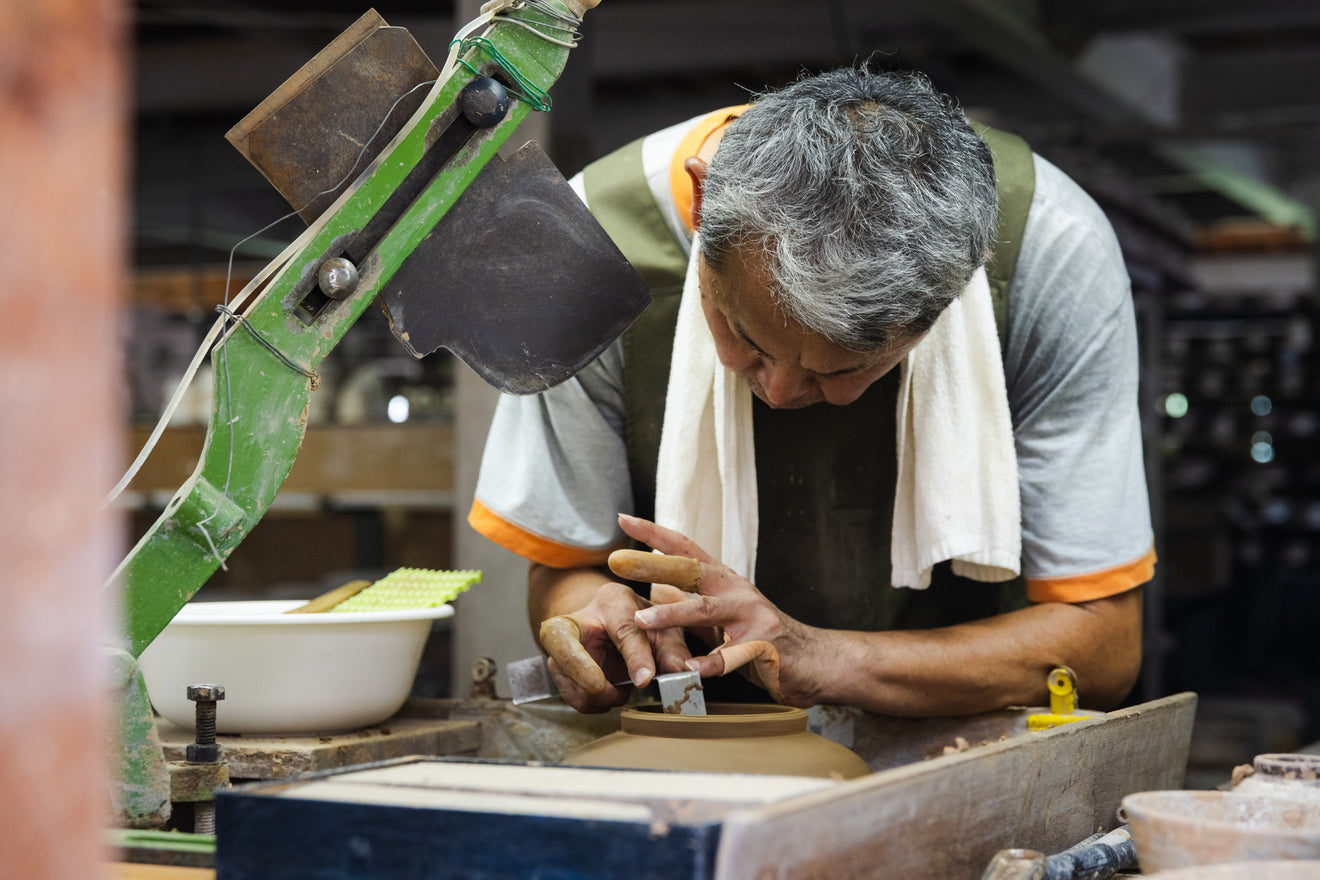 Japanese artisan carefully shaping a clay vessel on a pottery wheel at Rizaemon Kiln workshop in Nagasaki Japan