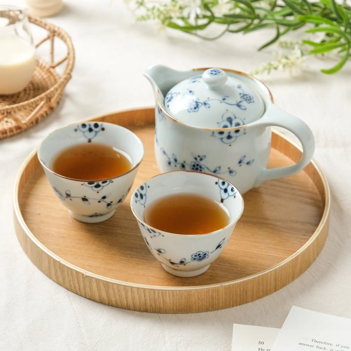 Vintage-style Japanese tea set with blue vine flower patterns, featuring a teapot and two teacups on a wooden tray.