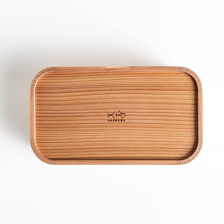 Top view of the Artisan Cedar Bento Box, highlighting the smooth lid with distinct horizontal grain and the subtle logo engraving in the center.